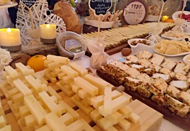 Mesa con quesos cortados y piezas enteras